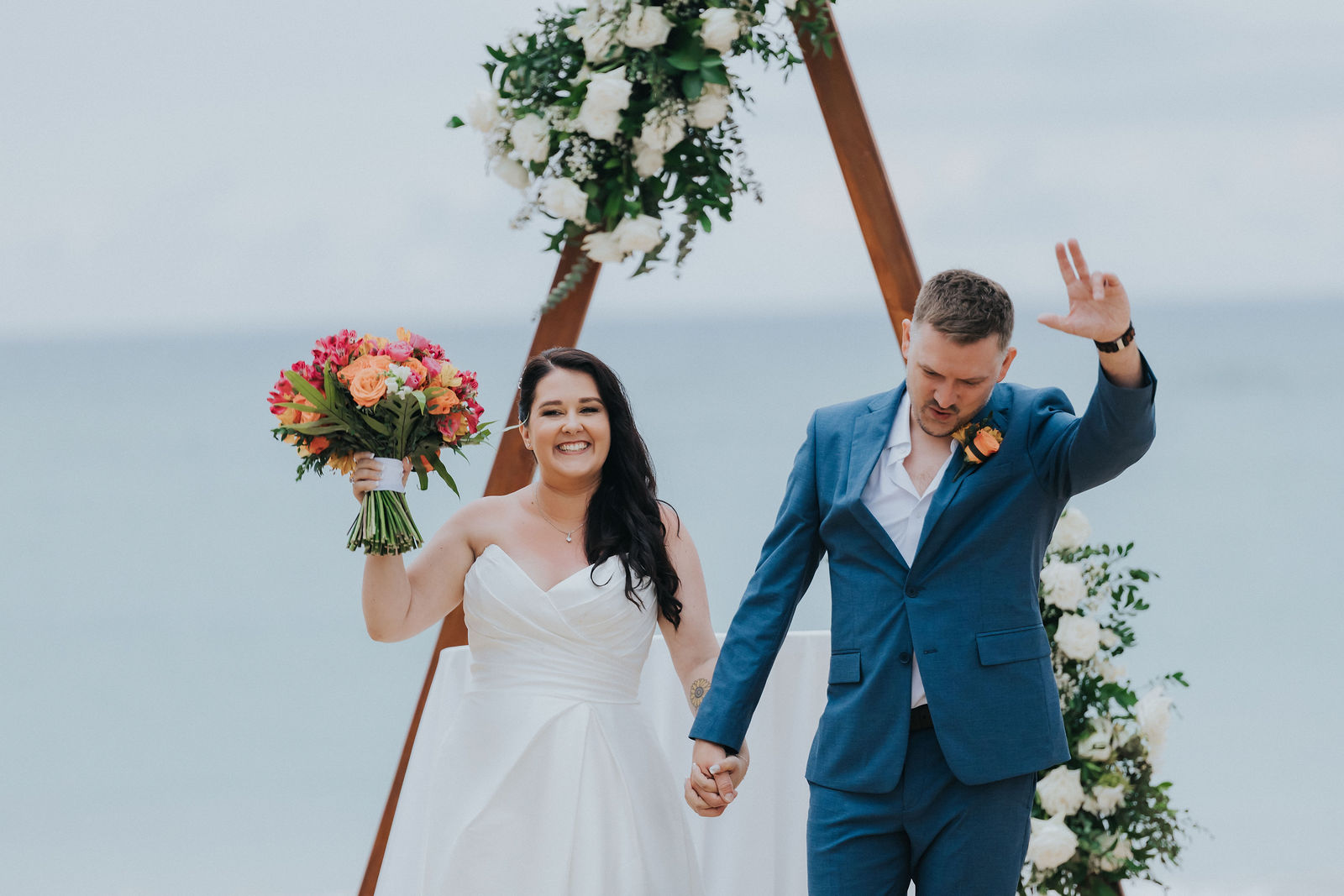 Newlyweds celebrating as they walk back down the sandy aisle
