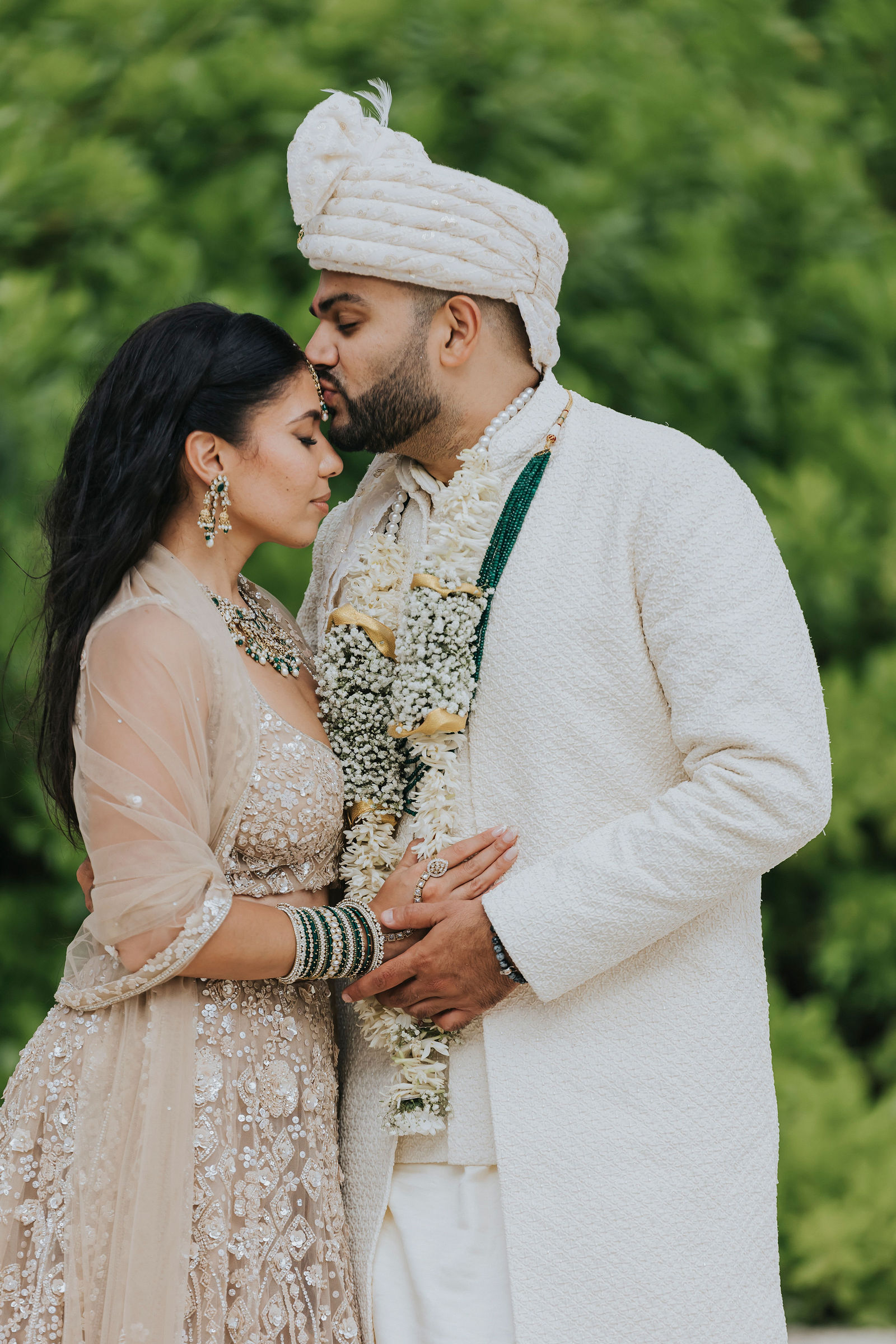 Groom kissing the bride's forehead in traditional attire
