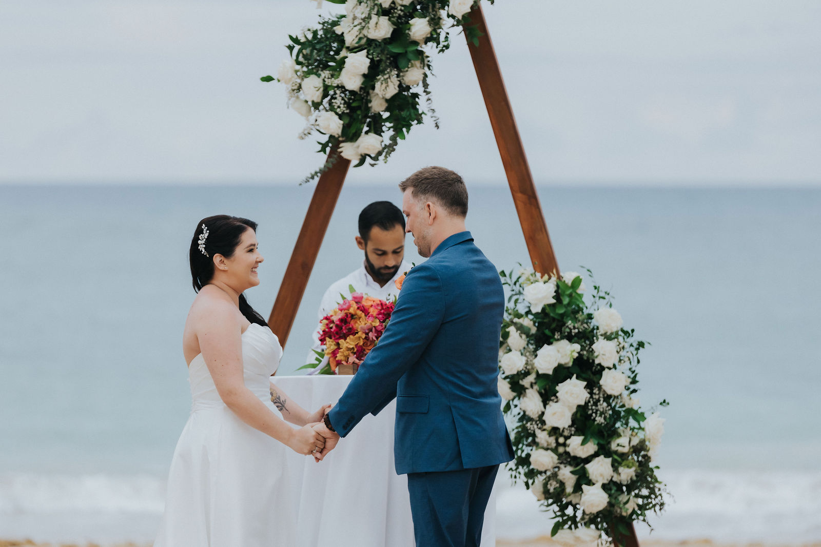 Beachfront ceremony arch dressed in white florals facing the Caribbean