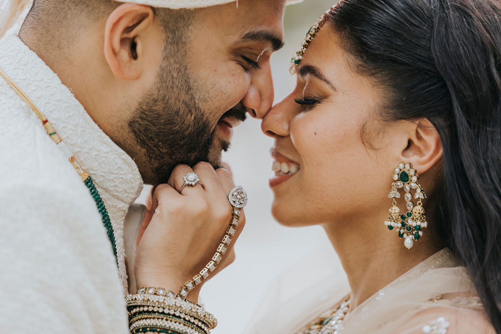 Bride and groom nose to nose, laughing, with bridal jewellery in detail