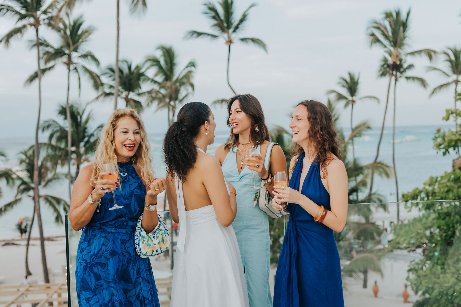 Group of friends toasting under tall palm trees