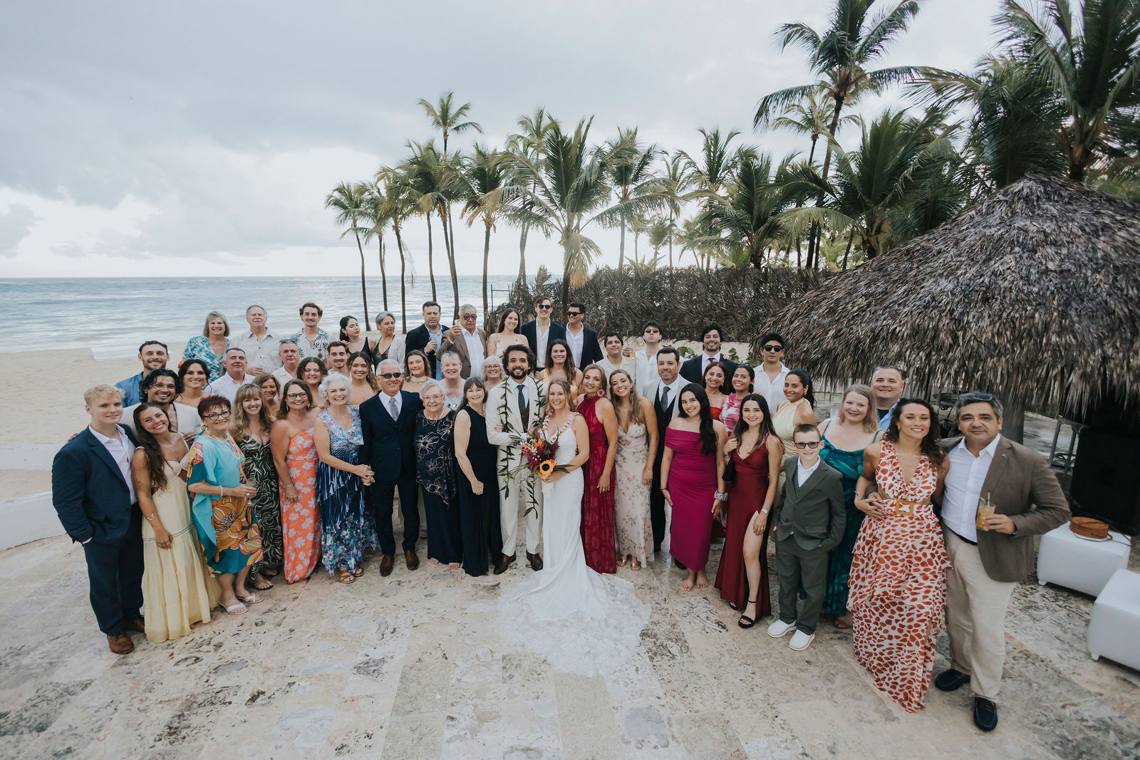 Wide group portrait of all the wedding guests on the beach