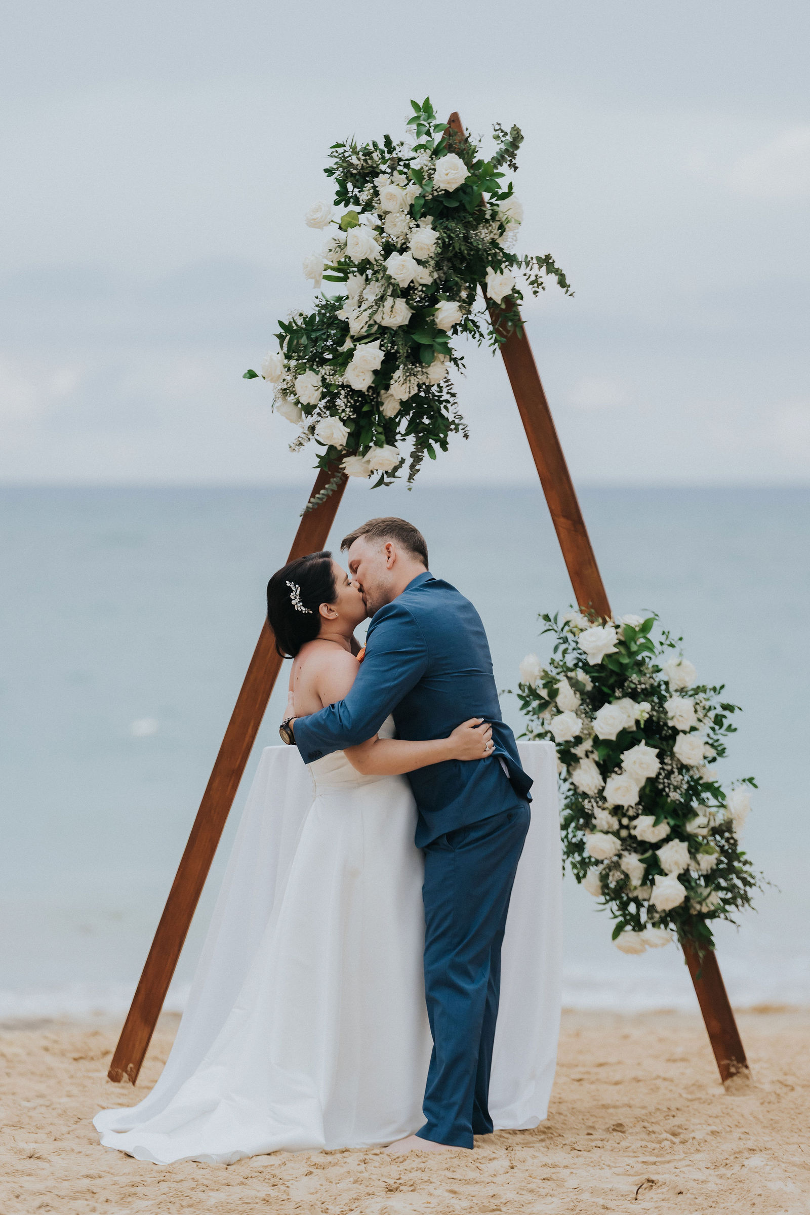 The couple's first kiss beneath the floral ceremony arch