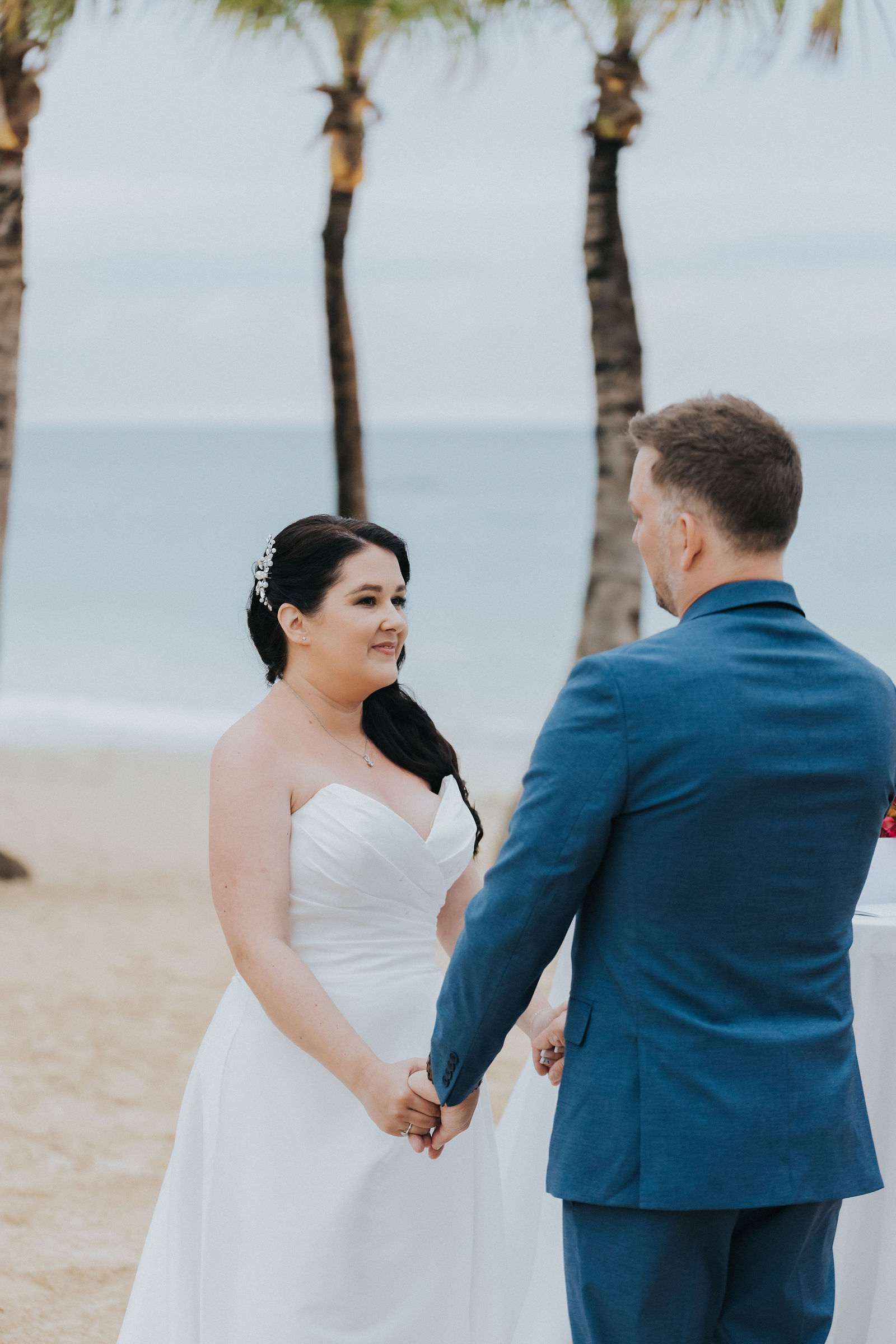 Bride and groom holding hands during their barefoot beach vows
