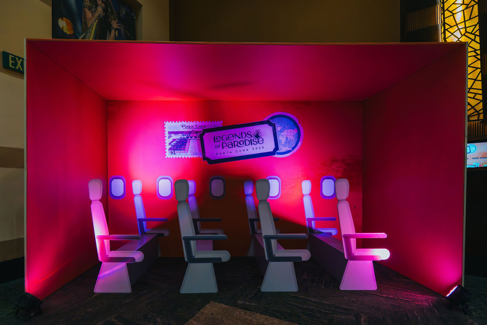 Travel-themed lounge installation with airplane seats and neon lighting