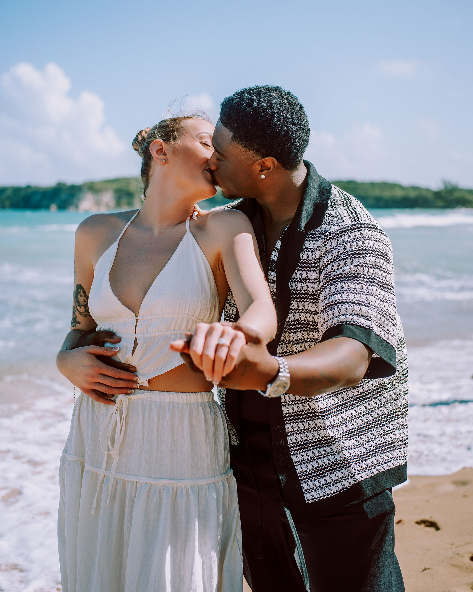 Newly engaged kiss along the shoreline at golden hour