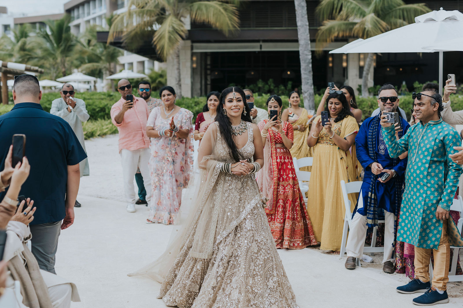 Family and guests in colourful saris walking to the beachfront ceremony