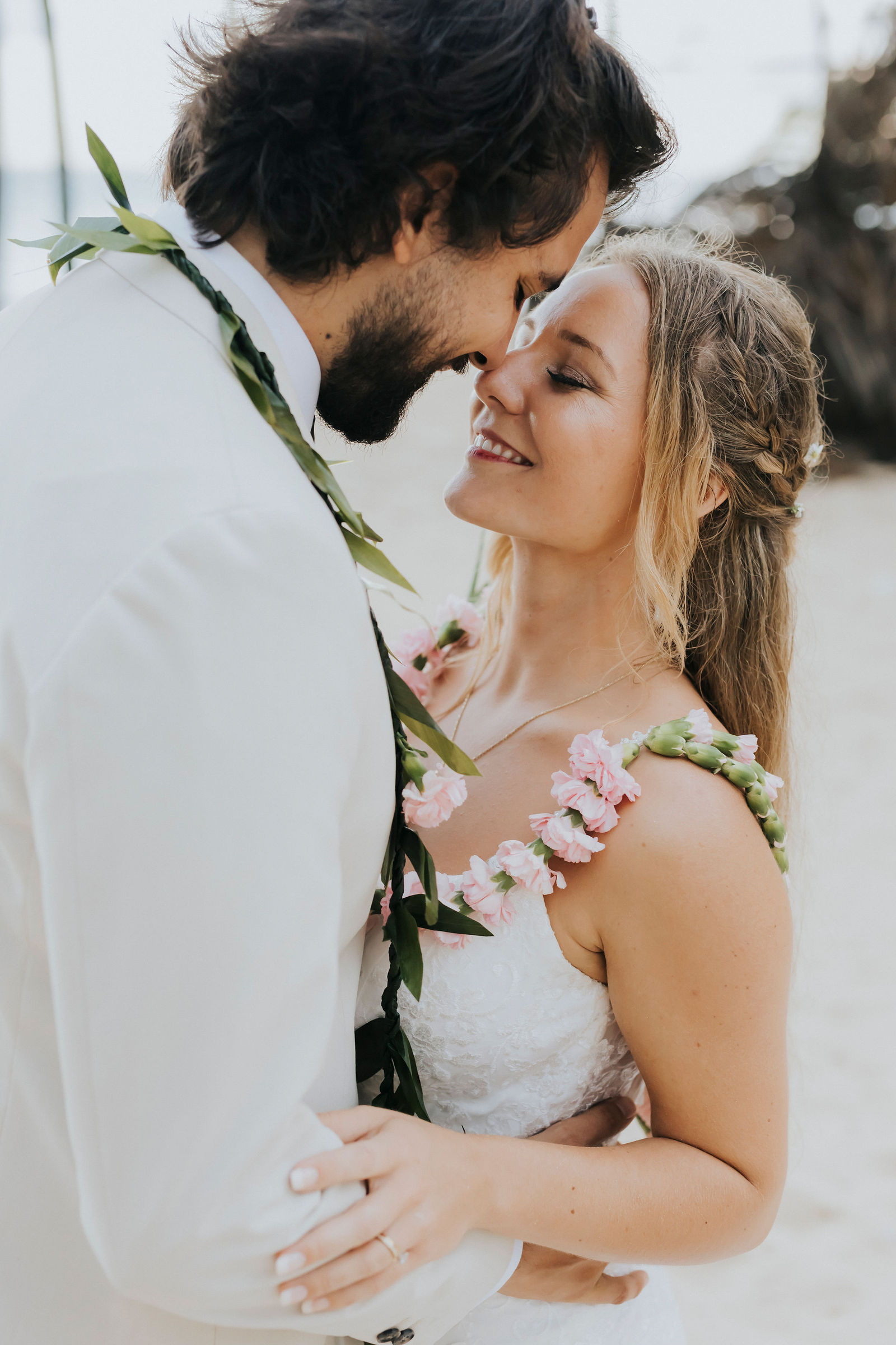 Bride and groom forehead to forehead wearing floral leis