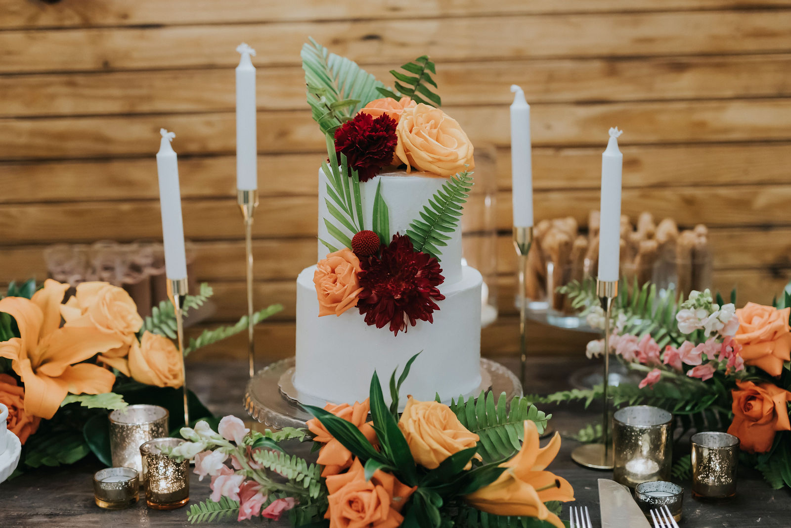 Wedding cake with tropical leaves and burgundy blooms