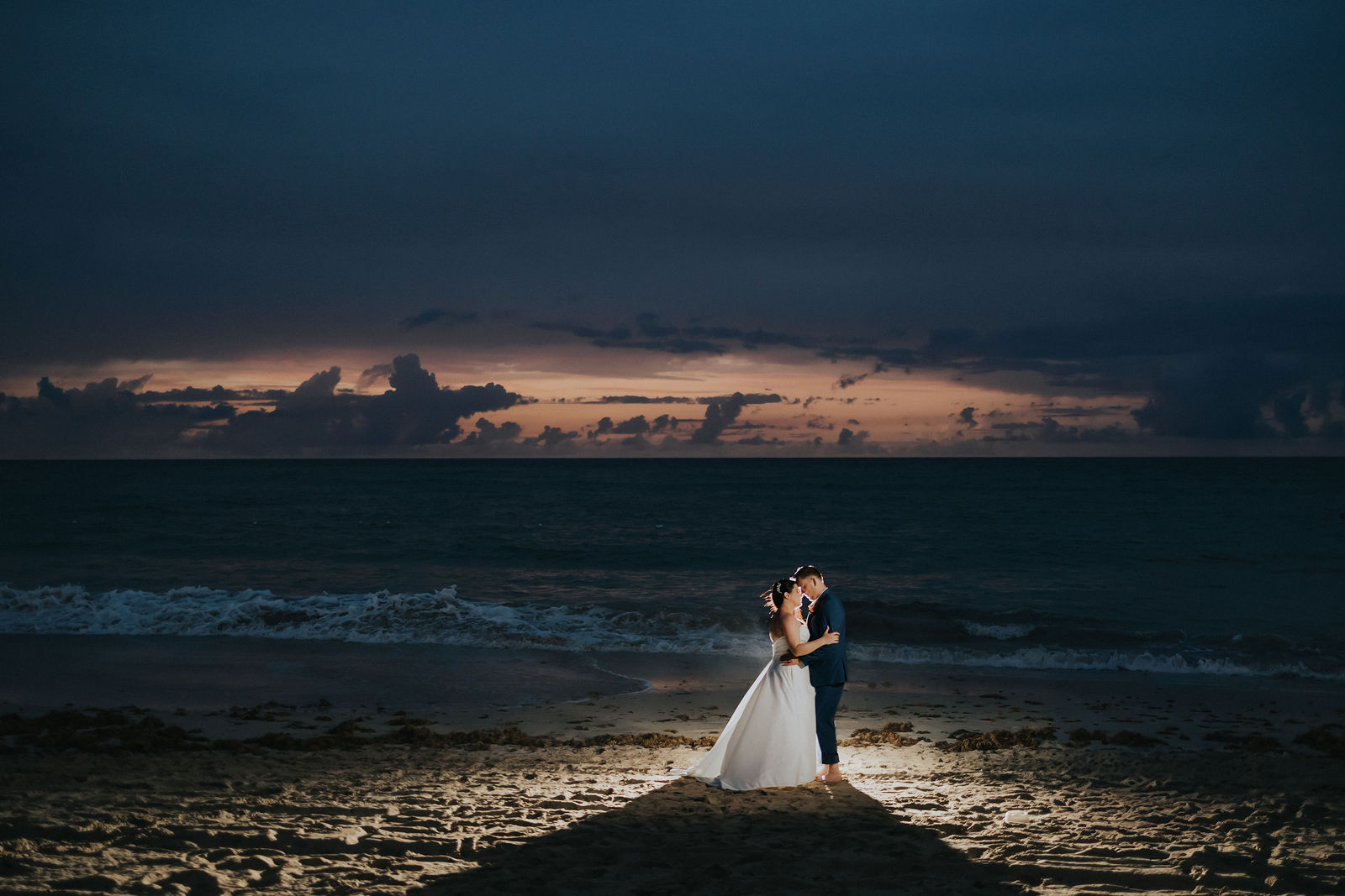 Silhouette of the newlyweds on the pier as the sun sets over the Caribbean