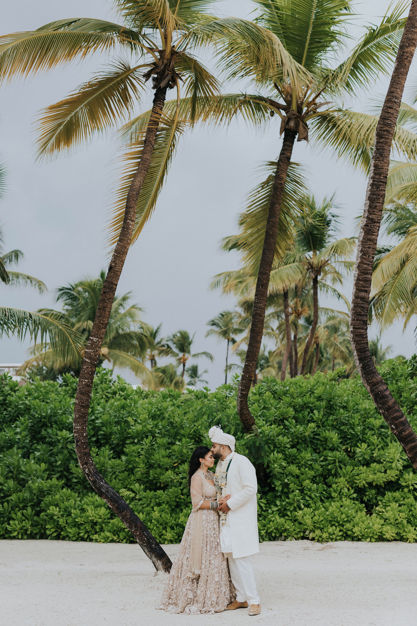 Couple embracing beneath tall palm trees in Punta Cana