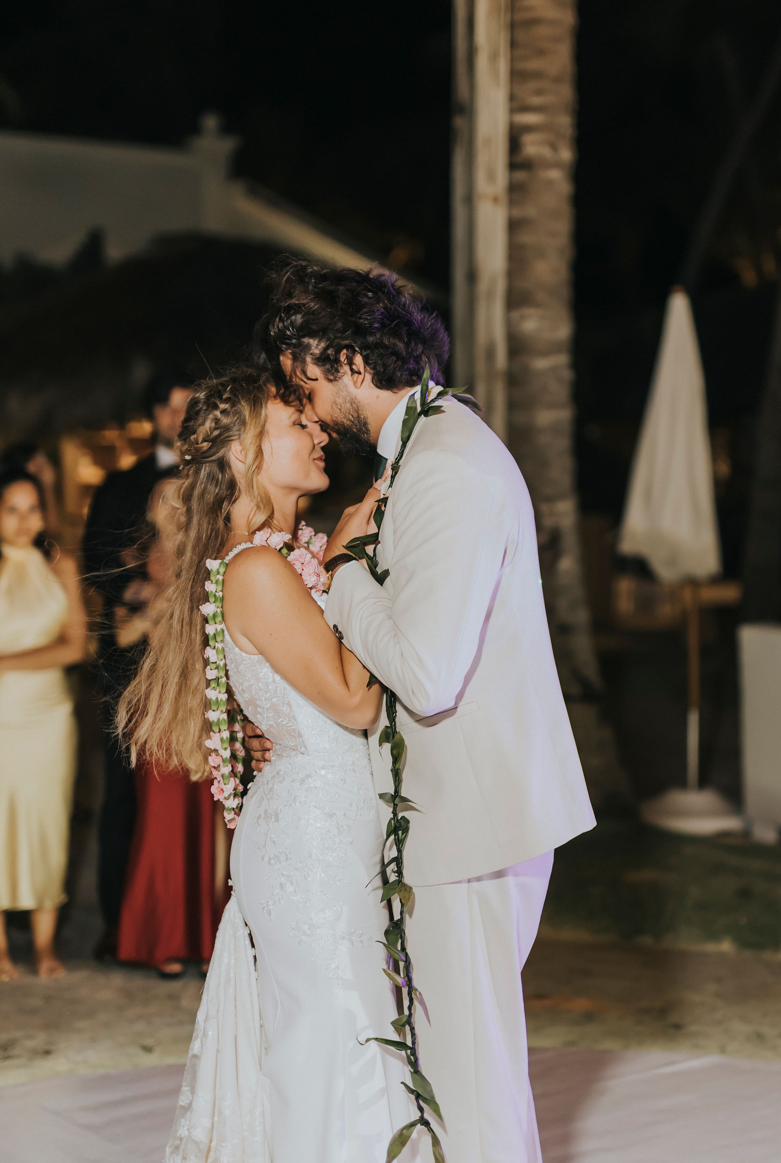 Bride and groom kissing during their first dance under string lights