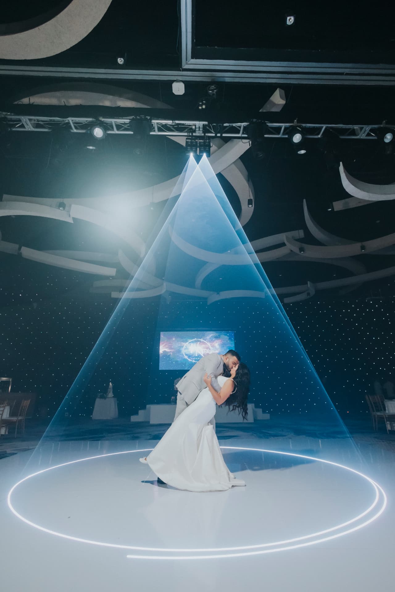Couple sharing a first dance under blue laser lighting at a wedding reception