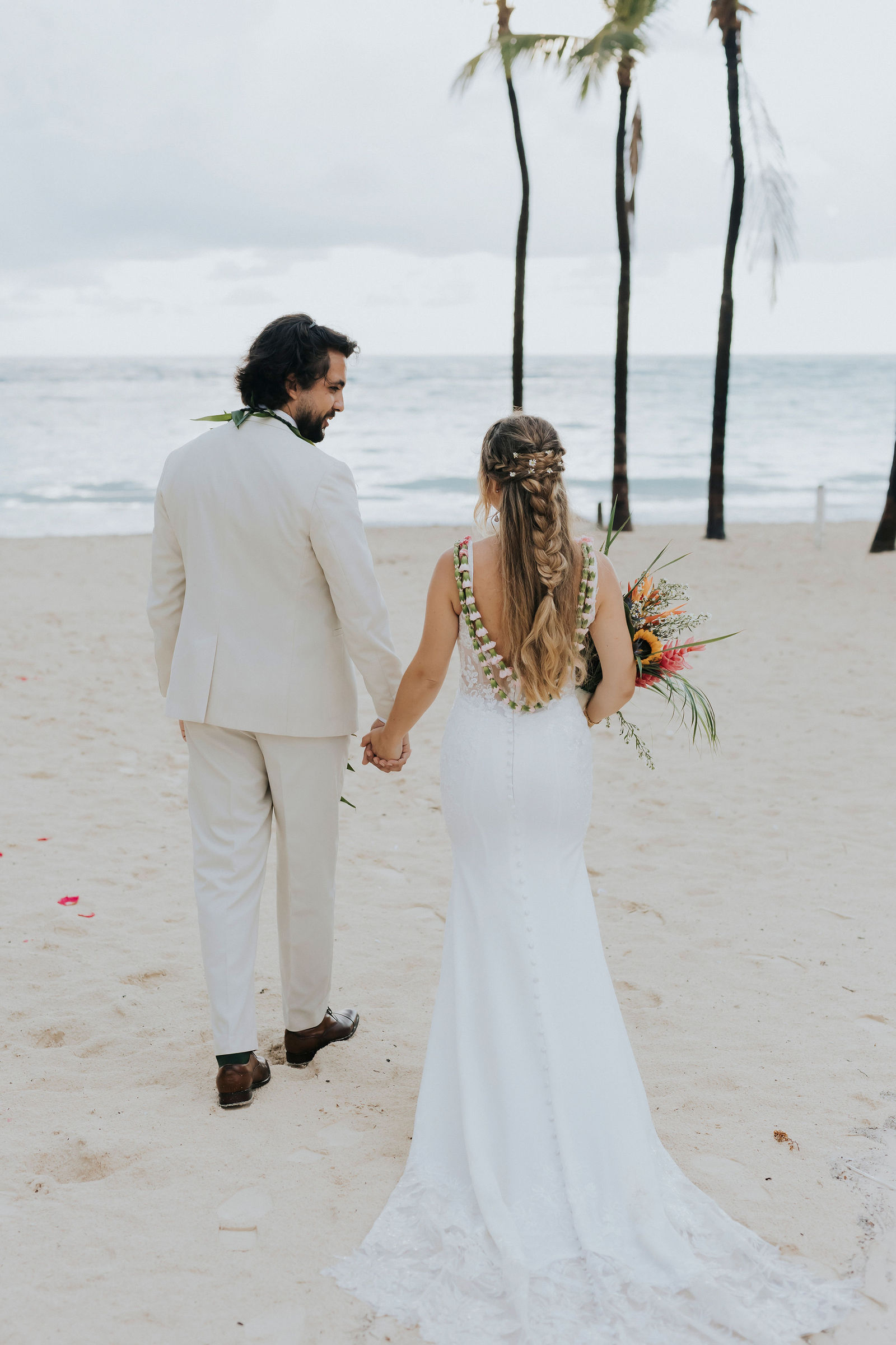 Bride and groom walking hand in hand along the shoreline