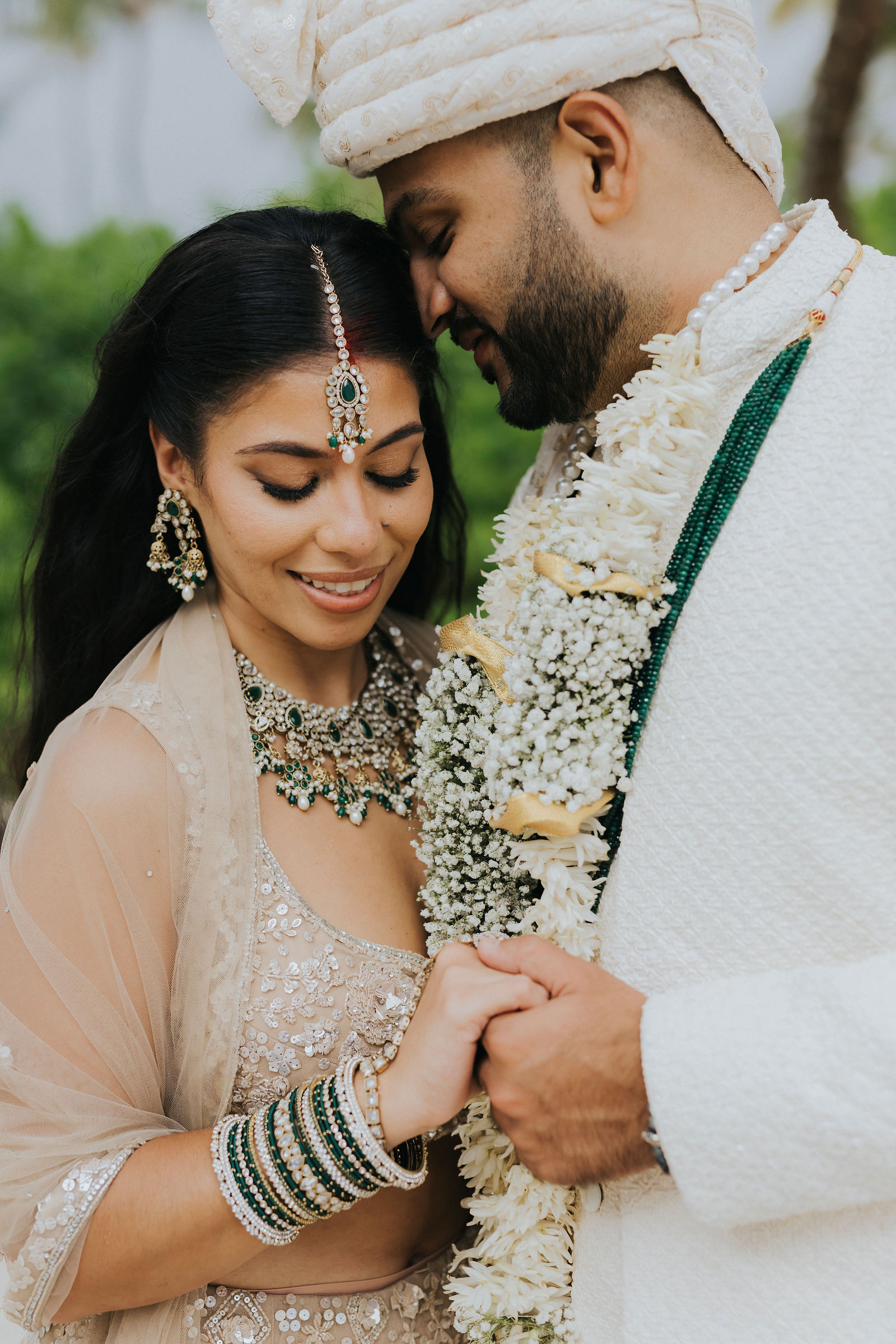 Bride and groom forehead to forehead wearing floral varmala garlands