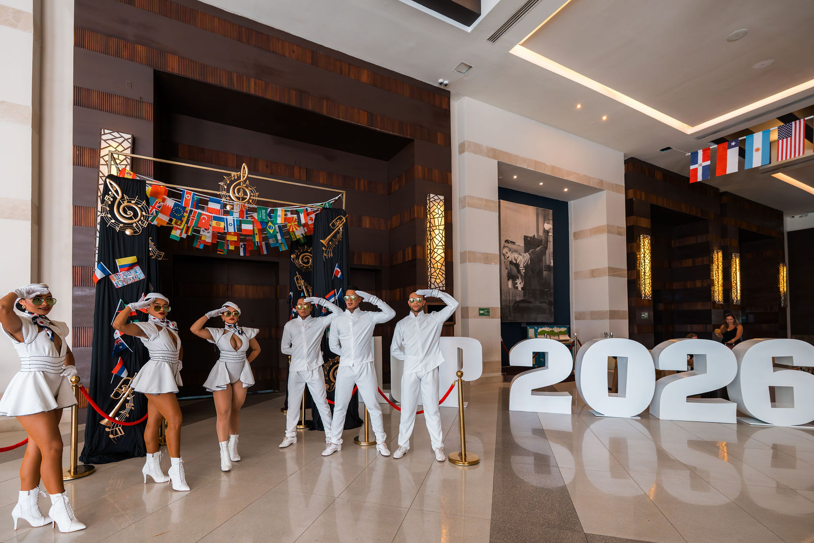Performers in pastel costumes posing beside the 2026 letters